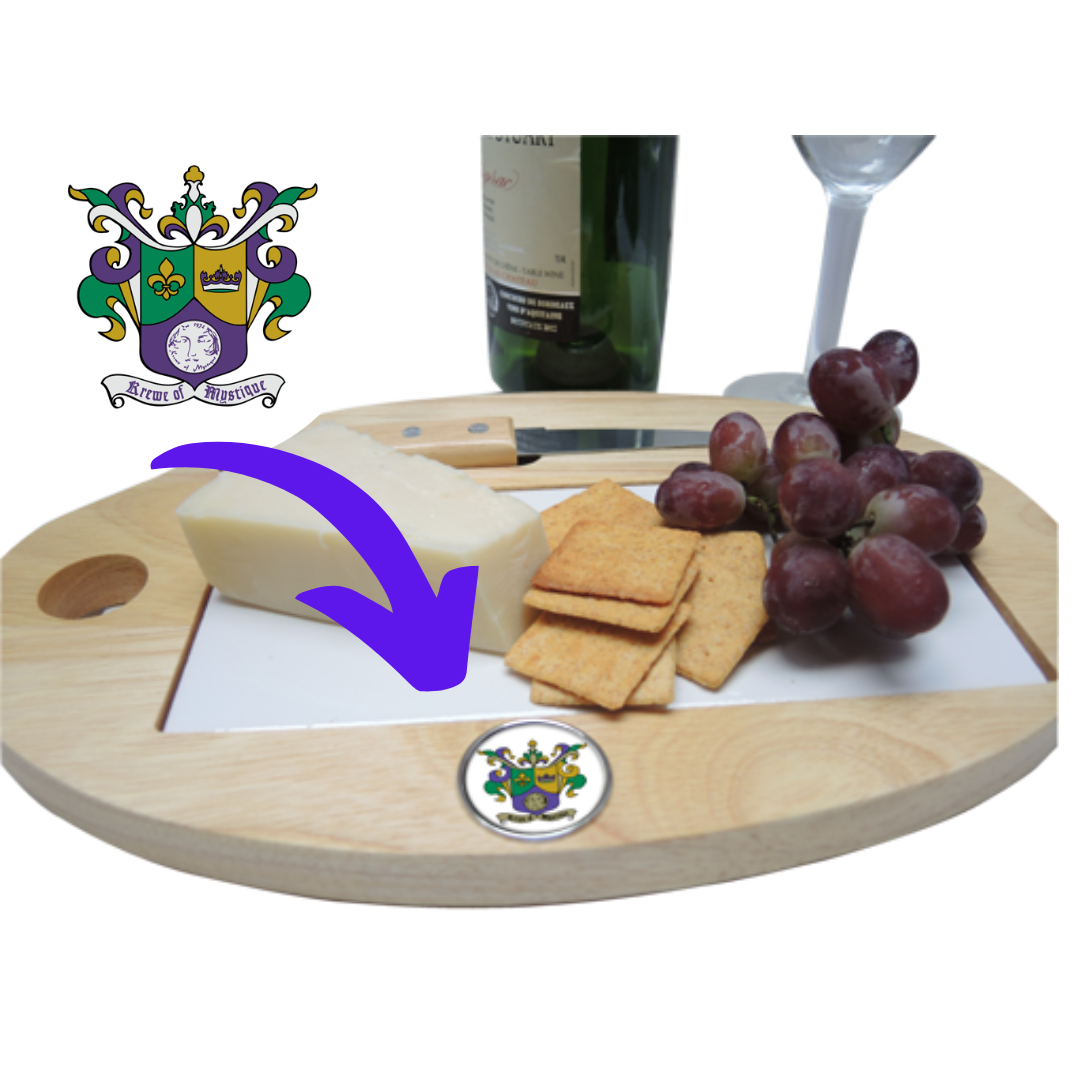 A wooden cheeseboard with a white tile top, featuring a silver medallion with a Mardi Gras Krewe logo, accompanied by grapes and crackers.