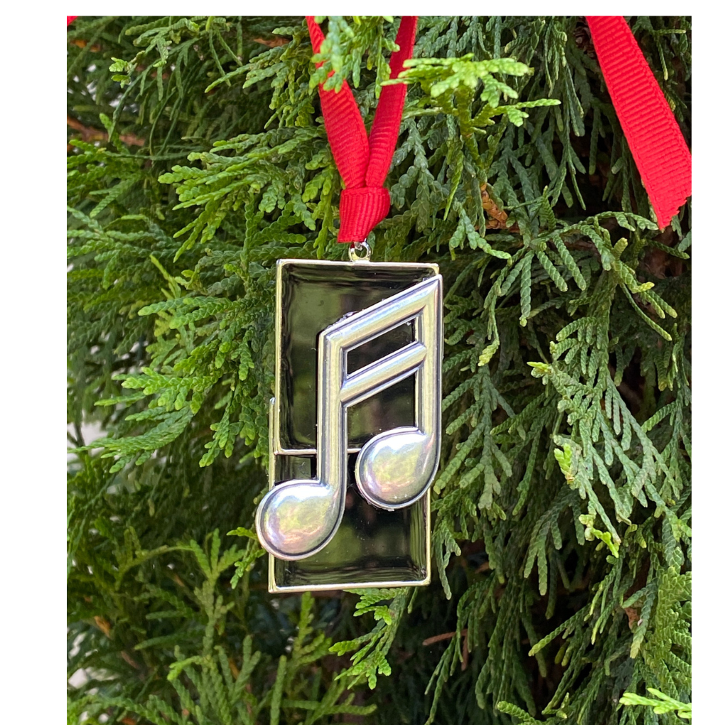 Decorative ornament shaped like a musical note hanging on a Christmas tree.