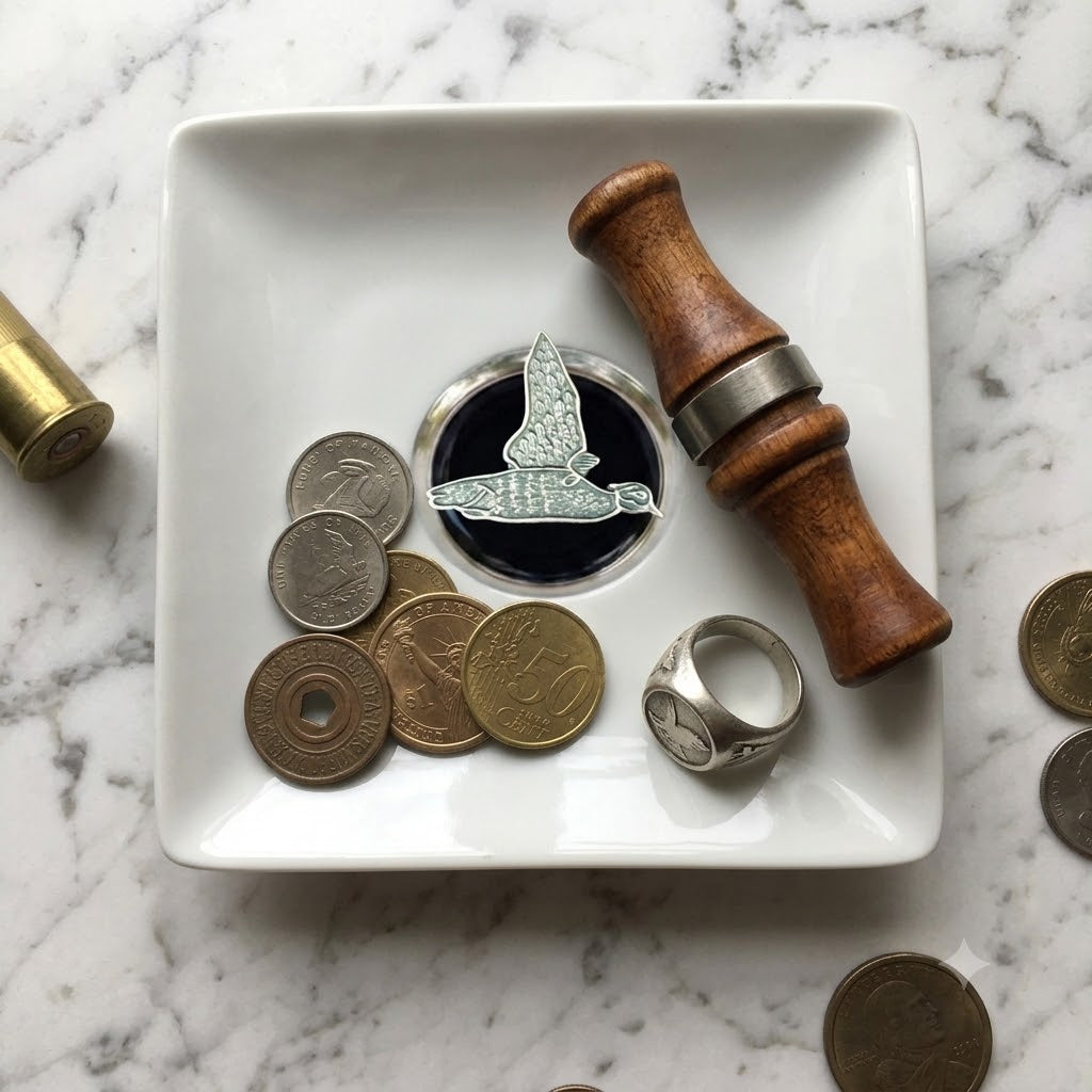 Our duck hunter theme trinket tray is white porcelain and features a large silver medallion with black enamel and a silver duck. This is a great gift for a duck hunter and duck lover.