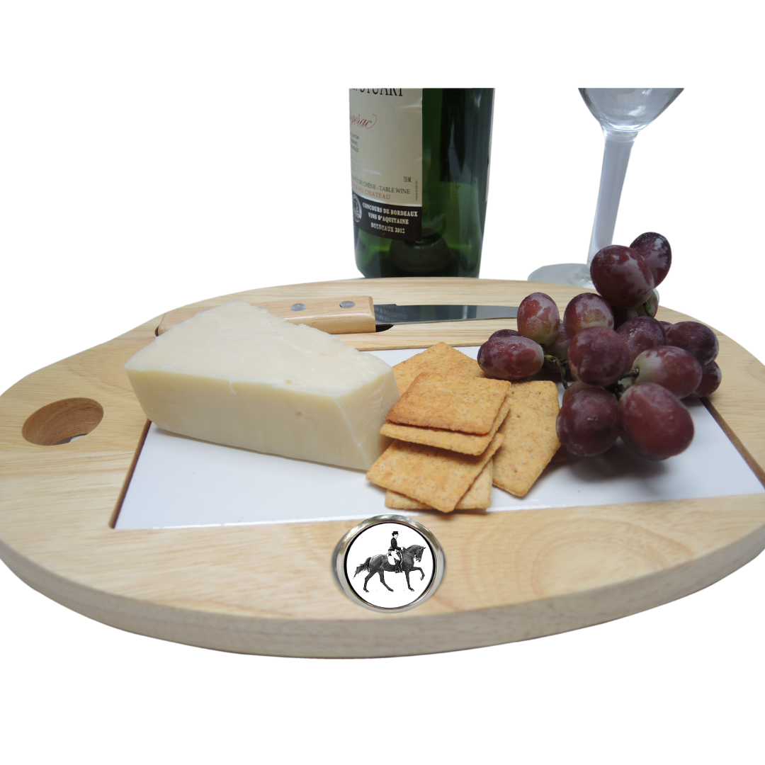 A cheeseboard with a silver equestrian dressage medallion, accompanied by cheese, crackers, and grapes. A wine glass and bottle are also visible in the background.
