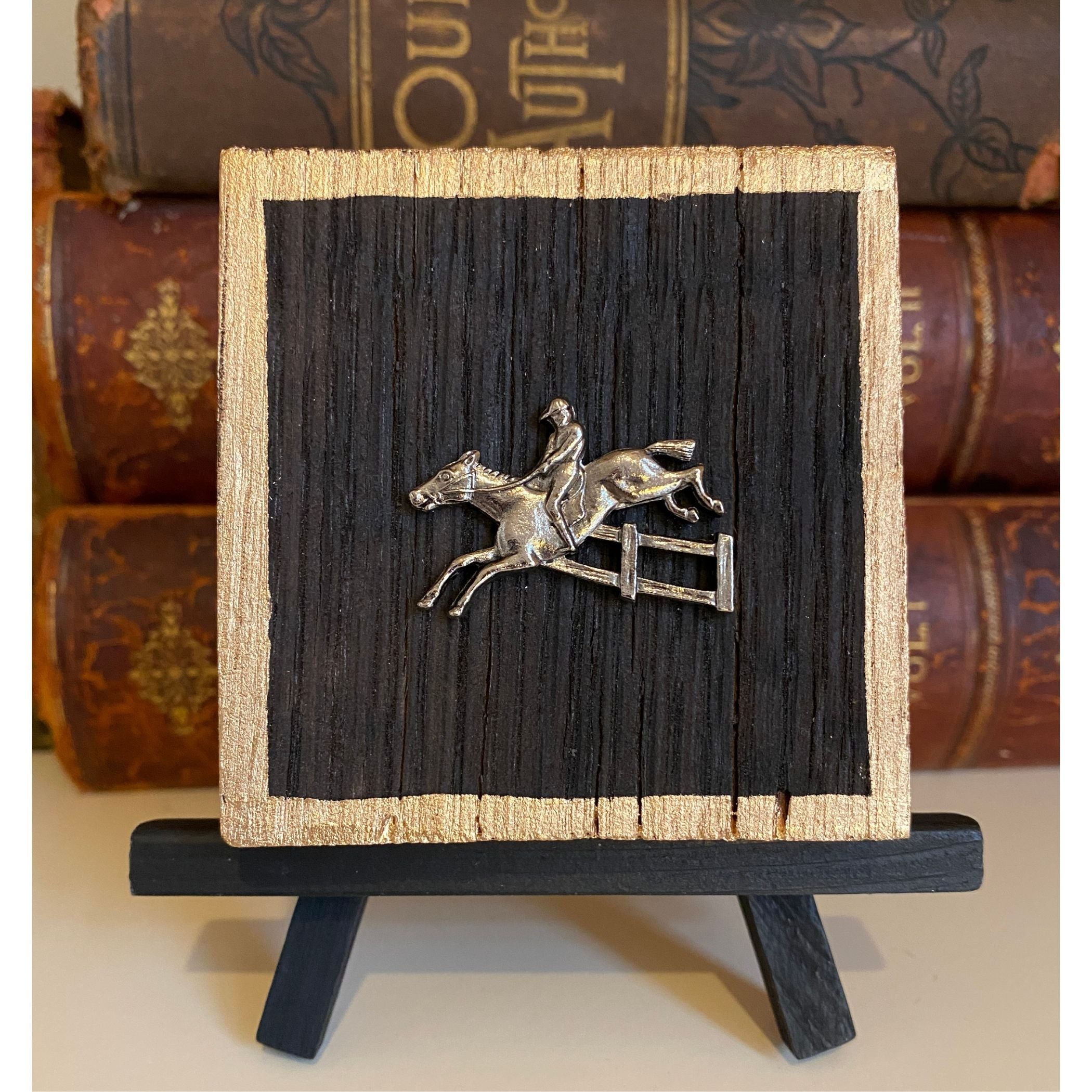 A wooden art piece featuring a central silver equestrian horse and rider medallion, with gold painted edges.