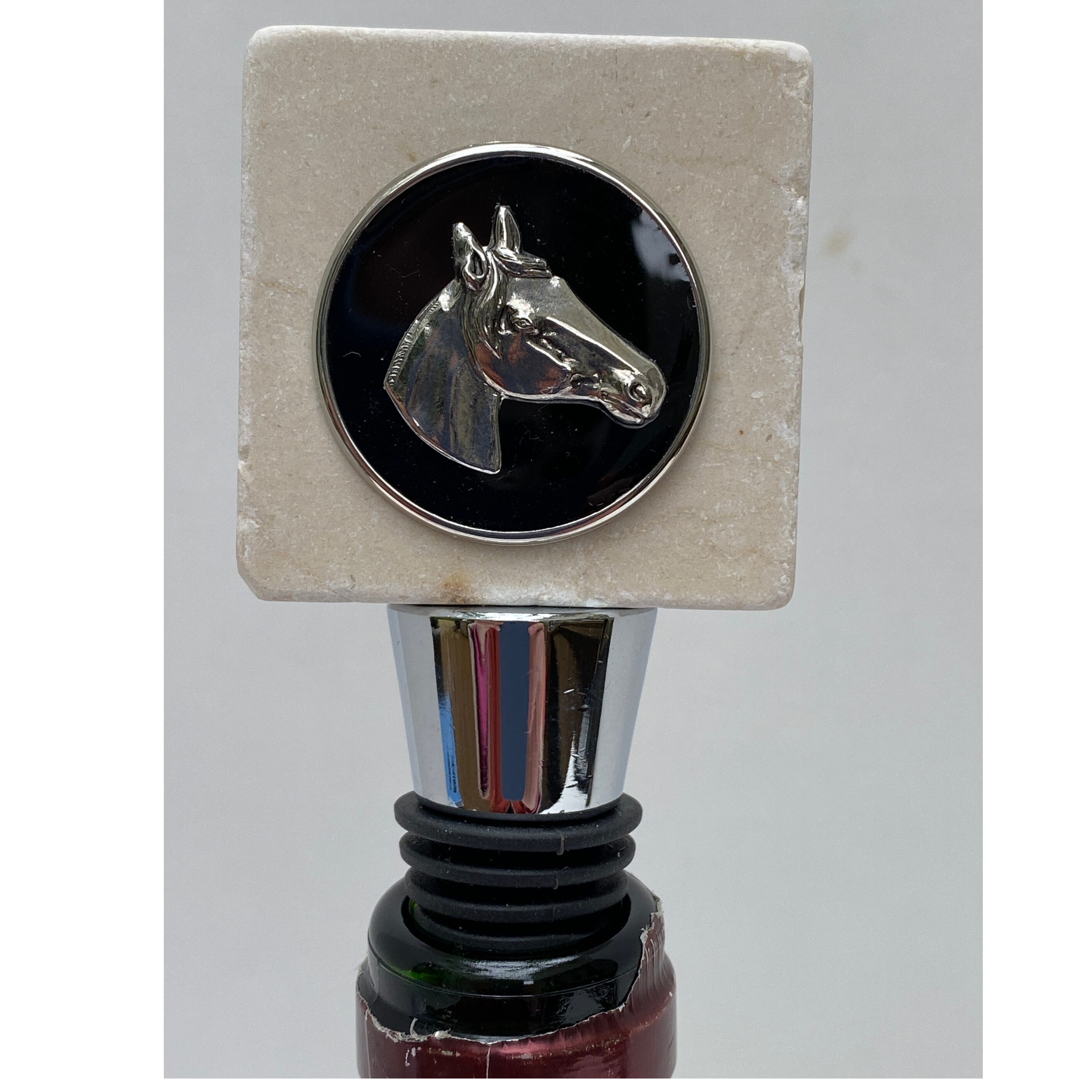 A marble bottle stopper with a silver horse head design on top. It is shown in a wine bottle.