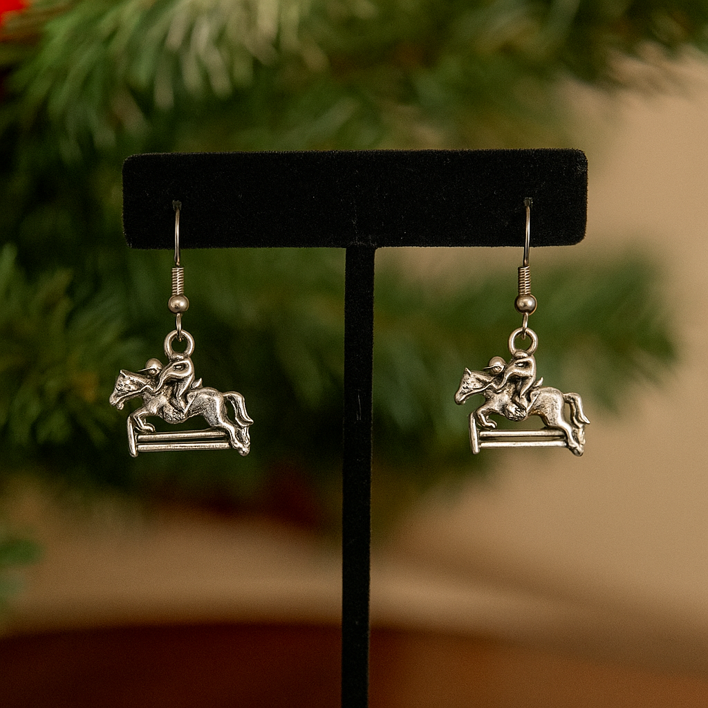 Silver hunter jumper equestrian-themed earrings on a black stand with a blurred green and brown background