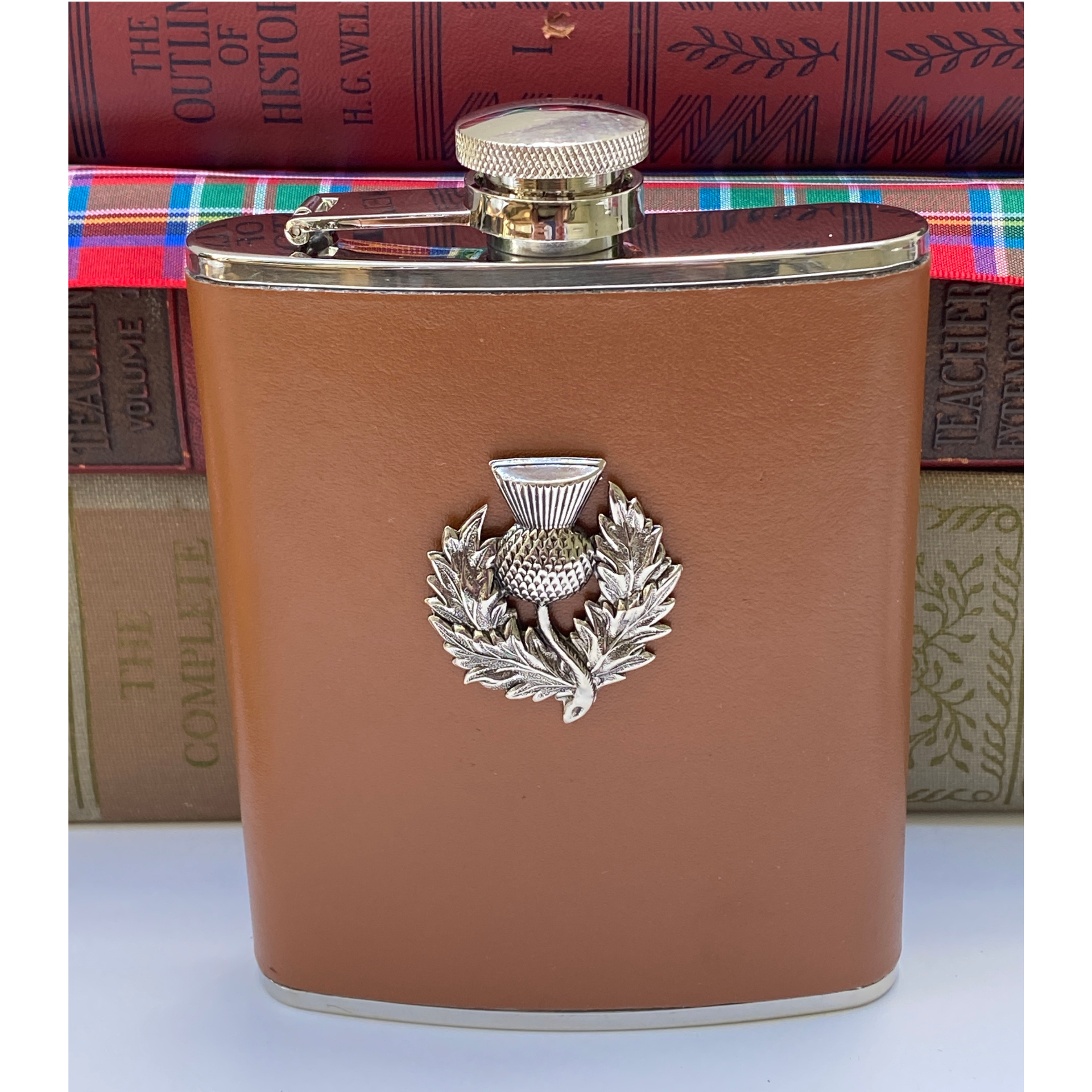 Brown leather flask with silver thistle emblem on a white background