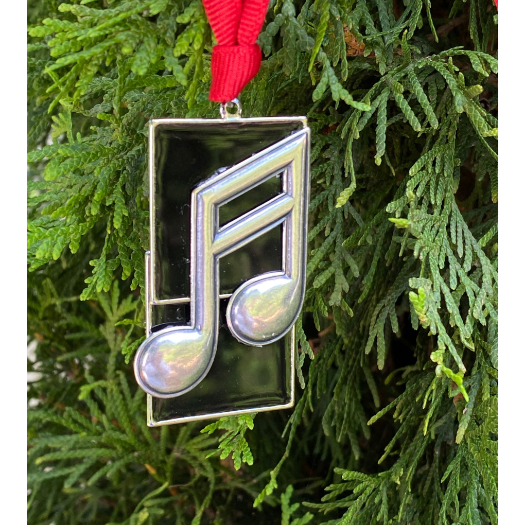 Decorative ornament shaped like a musical note hanging on a Christmas tree.