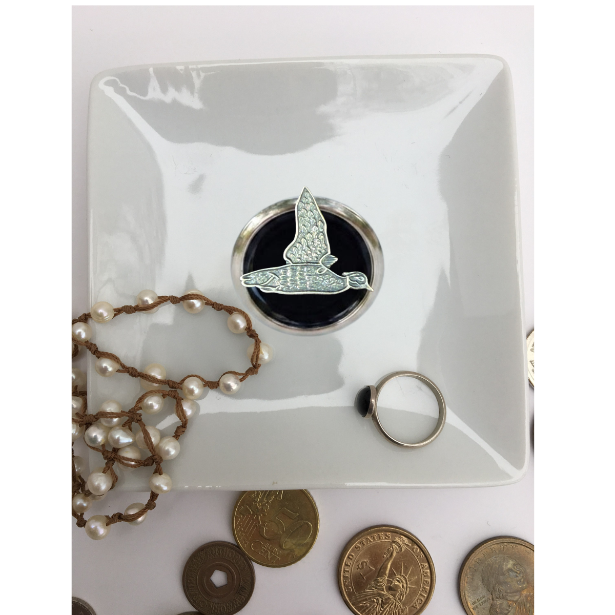 Our duck hunter theme trinket tray is white porcelain and features a large silver medallion with black enamel and a silver duck.   This is a great gift for a duck hunter and duck lover. 