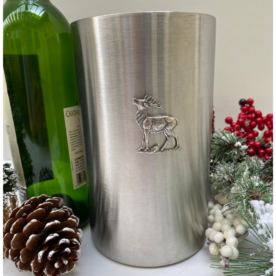 Stainless steel wine cooler with a silver medallion of a stag deer on the front, displayed with Christmas decorations in the background.