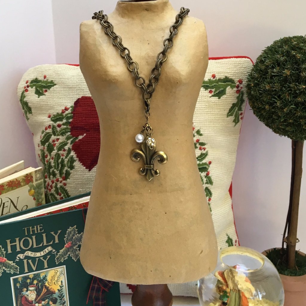 Our double link antique brass chain holds a stunning  antique gold fleur de lis embellished with crystal beads.   The necklace is 18" long and the closure is a toggle clasp.   This comes in a suede pouch for easy gift giving.  Sure to please fleur de lis lovers!   