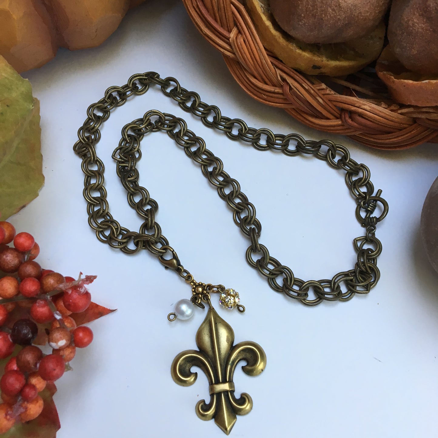 Our double link antique brass chain holds a stunning  antique gold fleur de lis embellished with crystal beads.   The necklace is 18" long and the closure is a toggle clasp.   This comes in a suede pouch for easy gift giving.  Sure to please fleur de lis lovers!