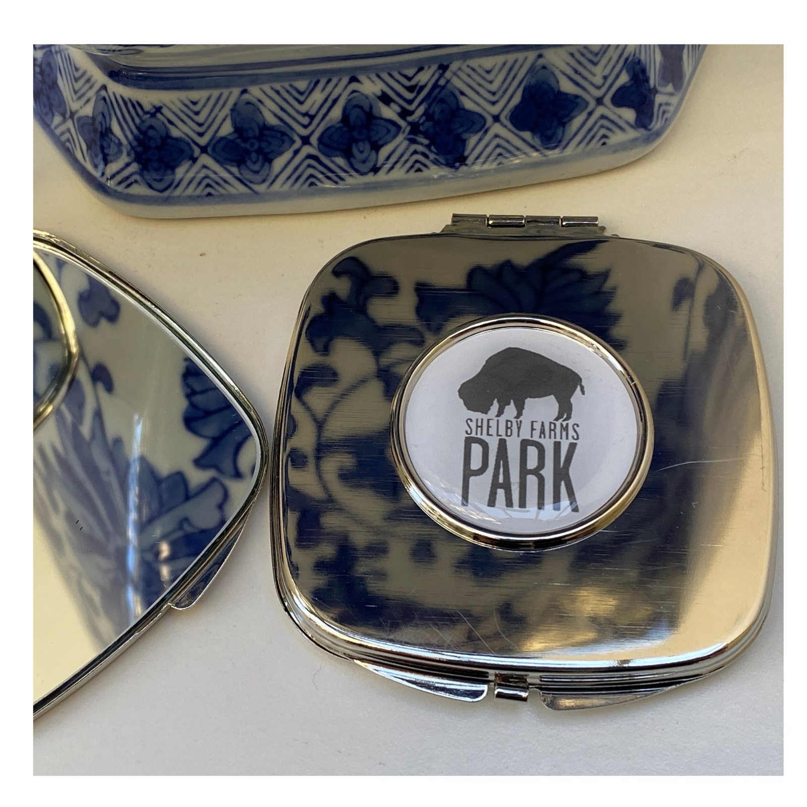 The custom purse mirror by Classic Legacy is a silver plate and features your logo inside a silver setting..  Open the mirror up, and you will find two mirrors.  One is single magnification, and the other is double magnification.  The mirror comes in a pouch.  This makes a great custom  logo gift.